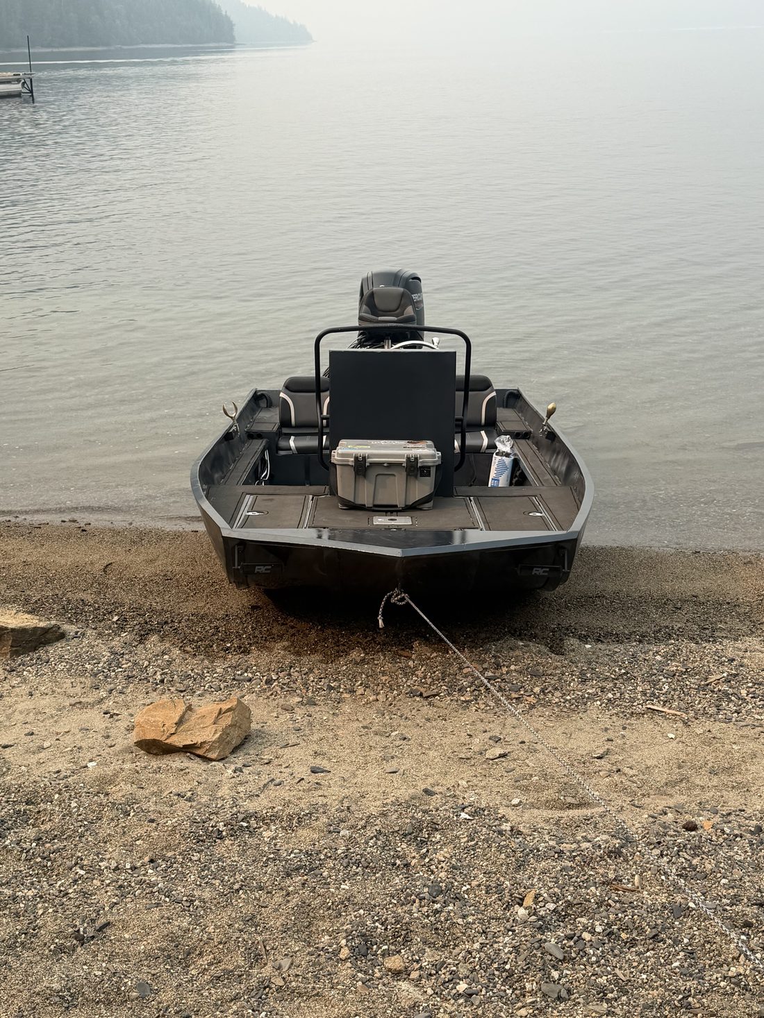 Boat pulled up bow-first on a sandy lakeshore