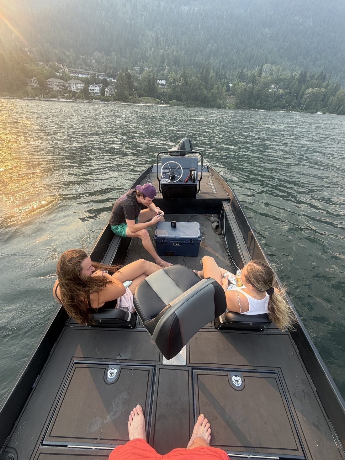 Three people relaxing aboard on a lake in the evening light